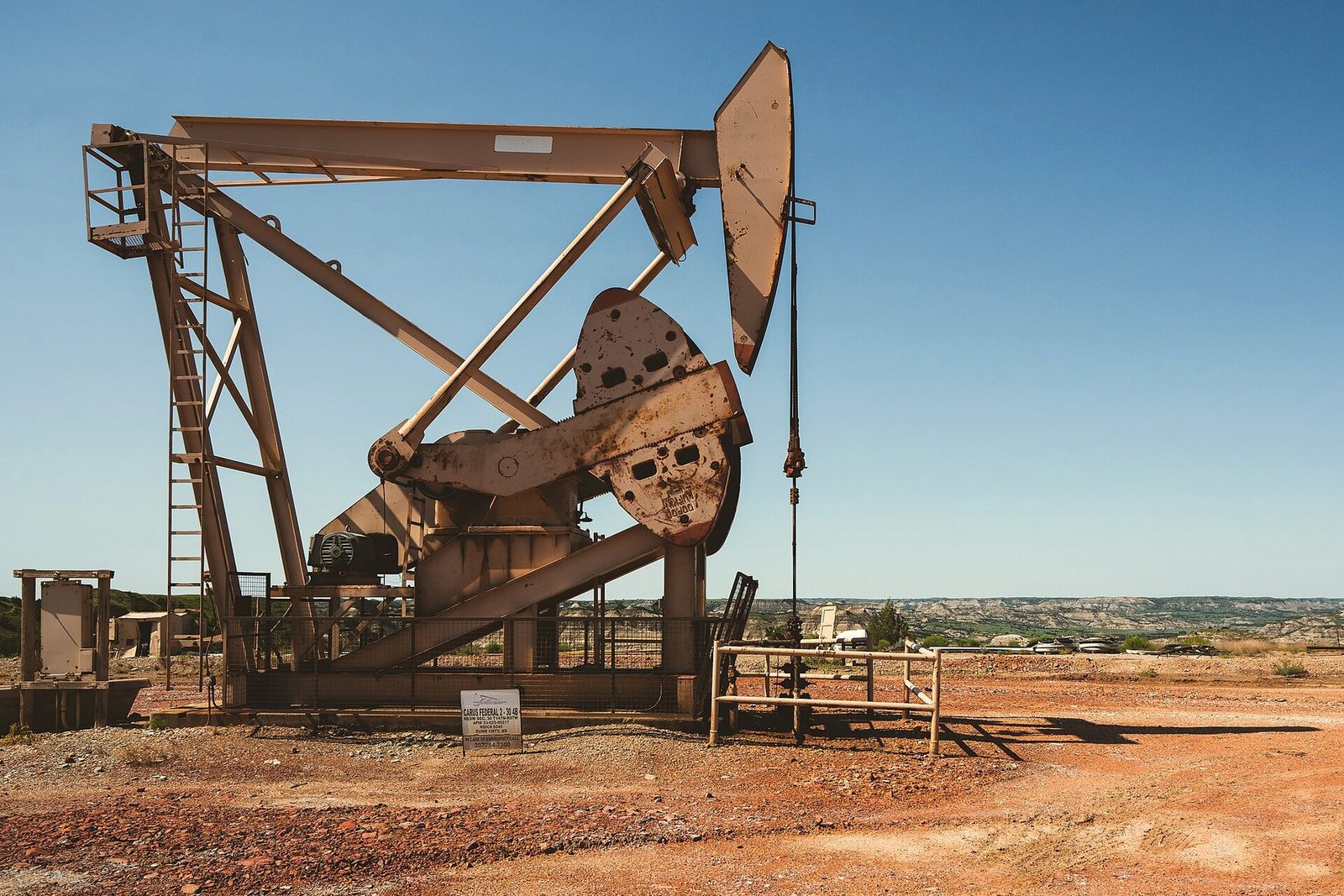 The weathered steel arm of a pump jack seen up close